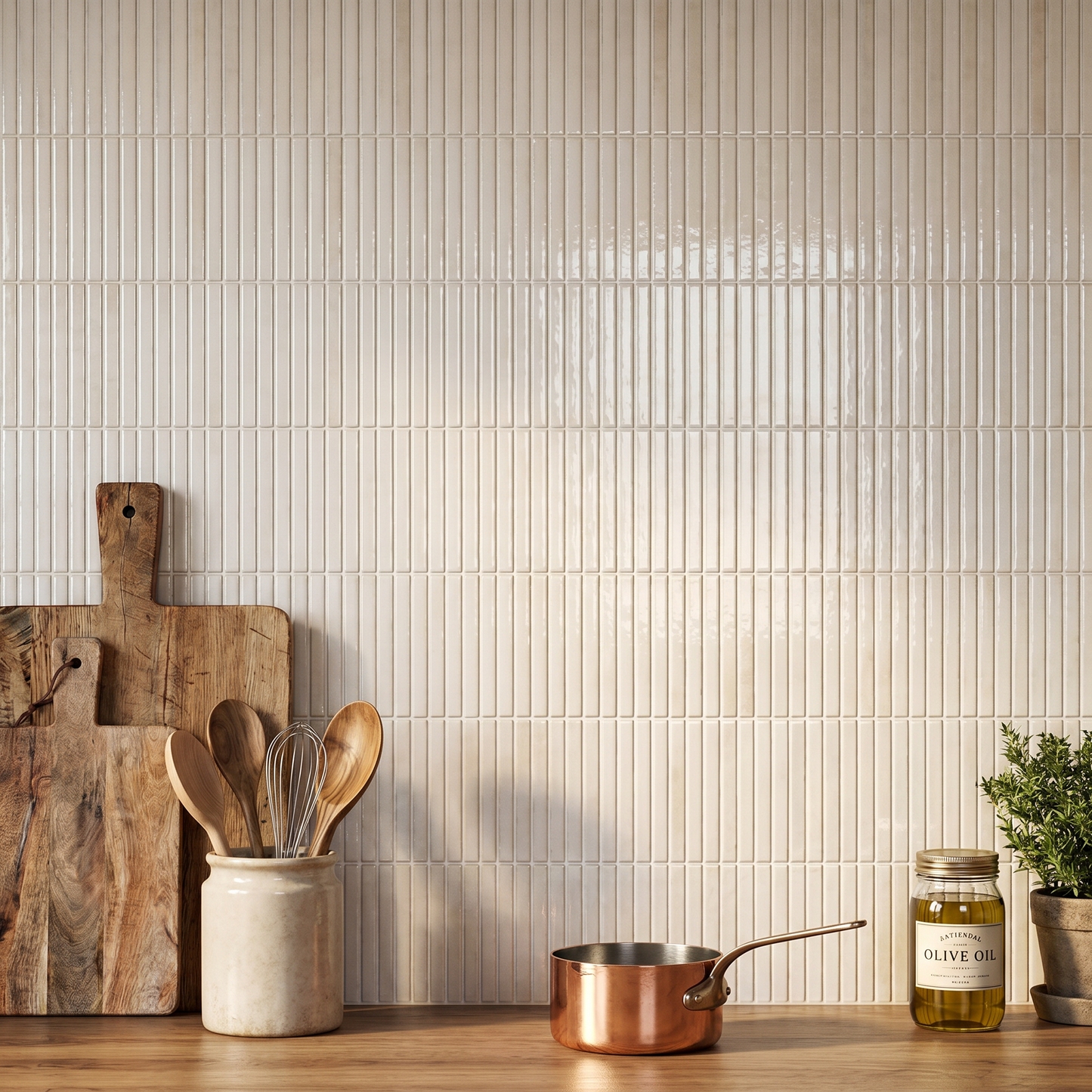 Kitchen counter with wooden cutting board, utensils, copper pot, and olive oil bottle against a tiled wall.